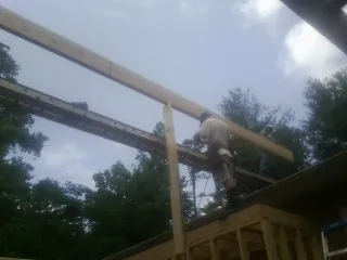 Carpenter setting a ridge beam over a new addition frame — Ice Dam Removal by Roofing Brothers in Gadsden
