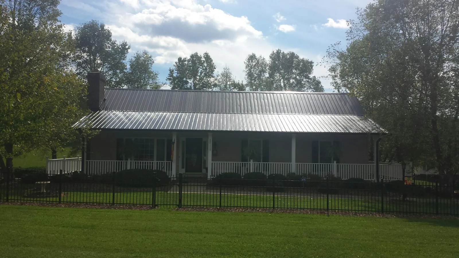 Gray metal roof on a brick ranch with a full width front porch — Gutter Guard Installation work by our crew in Gadsden