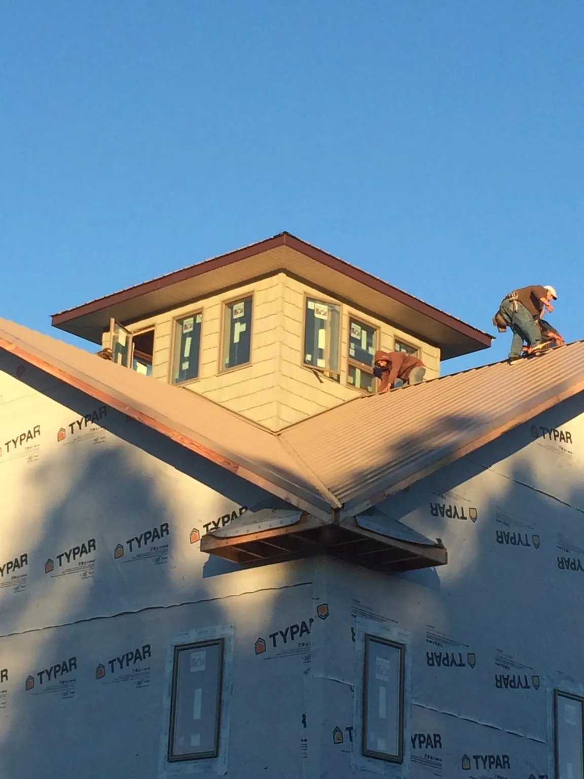 Roofers working around a rooftop cupola on a new metal roof at sunset — Roof Waterproofing in Gadsden by Roofing Brothers